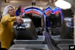 People wait for their belongings at the Transportation Security Administration security area at the Hartsfield-Jackson Atlanta International Airport, Jan. 25, 2023, in Atlanta, Ga.