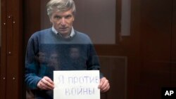 FILE - Alexei Gorinov holds a sign saying "I am against the war" while in a Moscow courtroom, June 21, 2022. He was the first person to be sentenced to prison under the law penalizing the spread of "false information" about Russian troops. Some of those convicted have been fined.