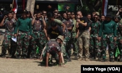 Peserta lomba berjalan menggunakan bakiak yang terdiri dari campuran prajurit dari berbagai negara berjatuhan setelah kaki mereka tidak kompak dalam melangkah. (VOA/Indra Yoga)
