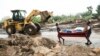 Men transport their salvaged belongings in Chiradzulu, southern Malawi, Friday March 17, 2023. 