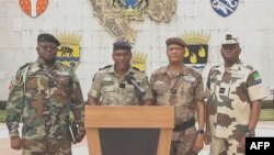 Kanali Ulrich Manfoumbi Manfoumbi (wapili kushoto) ambaye ni msemaji wa serikali ya mpito, akisoma taarifa kwenye televisheni ya Gabon, Septemba 7, 2023. Picha na Gabon 24 / AFP.