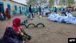 FILE - Internally displaced women wait to collect aid from a group at a camp in Gadaref on May 12, 2024. Clashes reignited between the Sudanese army and rival paramilitaries earlier this week in the key Darfur town of El-Fasher, the United Nations said.