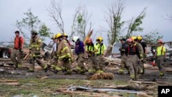 Firefighters walks among tornado-damaged homes, in Greenfield, Iowa, May 21, 2024.
