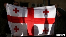 დემონსტრანტებს უჭირავთ საქართველოს ეროვნული დროშა, "რუსული კანონის" საწინააღმდეგო აქციაზე