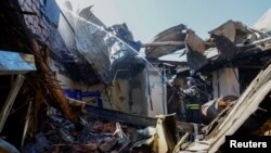 A firefighter works inside the burnt-out building of the University of Economics and Trade, which was reportedly hit by shelling in the course of Russia-Ukraine conflict in Donetsk, Russian-controlled Ukraine, Aug. 6, 2023. 