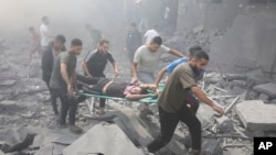 FILE - Palestinians evacuate wounded after an Israeli airstrike in Rafah refugee camp, southern Gaza Strip, Oct. 12, 2023.
