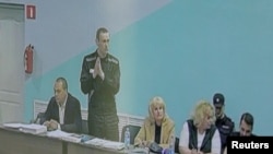 Russian opposition politician Alexei Navalny (standing) is seen on a screen via a video link during an external hearing of the Moscow City Court in a new criminal case against Navalny in the Vladimir region, Russia, June 19, 2023.