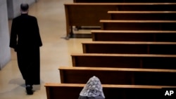 Seorang perempuan duduk sendirian sebelum Misa Katolik di Benedictine College di Atchison, Kansas, Minggu, 29 Oktober 2023. (AP Photo/Charlie Riedel)