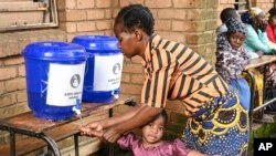 A child has her hands washed at a displacement center in Blantyre, southern Malawi March 16, 2023. 