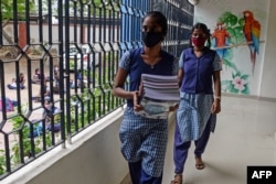 FILE - Students collect text books before attending a tele-learning class at their home, as schools remained closed due to COVID-19 coronavirus in Chennai, July 15, 2020.