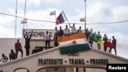 FILE - Men hold Niger and Russian flags as they gather with thousands of anti-sanctions protesters in support of the putschist soldiers in the capital Niamey, Niger, Aug. 3, 2023.