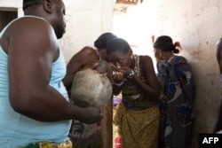 Pengikut voodoo mengikuti ritual dengan meminum air di biara Dah-Gbo Zonon saat festival voodoo di Ouidah, Benin, pada 10 Januari 2023. (Foto: AFP)