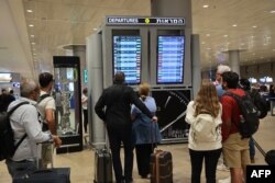 Passengers look at a departure board at Ben Gurion International Airport near Tel Aviv, Israel, as flights are canceled because of the Hamas attacks, Oct. 7, 2023.