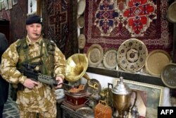 ILUSTRASI - Seorang tentara Inggris berpose di sebuah toko yang memajang karpet tua dan barang antik saat berpatroli di distrik kota lama Basra, Irak, 23 Februari 2004. (AFP /Hani AL-OBEIDI)