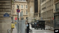 FILE - A police officer attaches fences at the security perimeter at the 2024 Summer Olympics, July 21, 2024, in Paris. France has been on high alert over the past few weeks as preparations to host the Olympics hit the final stretch. 