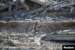 27일 가자지구 남부 칸 유니스에 이스라엘 군의 공습으로 파괴된 학교 쉼터 앞을 팔레스타인 어린이가 지나가고 있다.