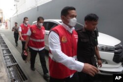 Polisi, dari kanan ke kiri, Bambang Sidik Achmadi, Has Darmawan dan Wahyu Setyo Pranoto dikawal oleh petugas saat berjalan ke ruang sidang pengadilan negeri di Surabaya, Kamis, 16 Maret 2023. (AP/Trisnadi)