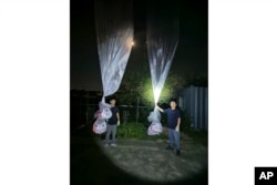 Pembelot Korea Utara Park Sang-hak (kiri) dan anggota Fighters For A Free North Korea memegang balon bertuliskan selebaran propaganda anti-Korea Utara di Paju, Korea Selatan, dekat perbatasan dengan Korea Utara, Kamis, 20 Juni 2024. (Pejuang Untuk Korea Utara yang Merdeka via AP)