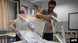 Election officials empty a ballot box to count the votes at a polling station during general elections in Thessaloniki, on June 25, 2023. 