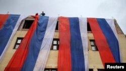 Para aktivis etnis Serbia mengibarkan bendera Serbia Bosnia di sebuah gedung, yang dilarang oleh mahkamah konstitusi Bosnia dan Herzegovina, di Sarajevo Timur (foto: dok). 