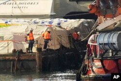 Staffers of port, left, stand on the aid platform and Open Arms aid group on the ship as it prepares to ferry some 200 tons of rice and flour directly to Gaza, at the port in Larnaca, Cyprus, March 10, 2024.