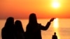 FILE - A parishioner is silhouetted against the rising sun as she prays during an Easter sunrise service held by Park Community Church, April 4, 2021, at North Avenue Beach in Chicago.