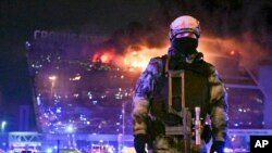 Un militaire russe de la Garde nationale sécurise une zone alors qu'un incendie massif est observé au-dessus de l'hôtel de ville de Crocus, à Moscou, en Russie, le vendredi 22 mars 2024. ((AP Photo/Dmitry Serebryakov)
