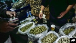 FILE - A vendor makes change for a marijuana customer at a cannabis marketplace in Los Angeles, April 15, 2019. 
