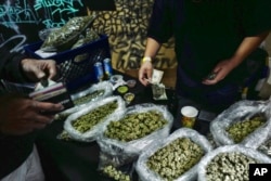 FILE - A vendor makes change for a marijuana customer at a cannabis marketplace in Los Angeles, April 15, 2019.