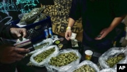 FILE - A vendor makes change for a marijuana customer at a cannabis marketplace in Los Angeles, April 15, 2019. 