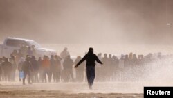 Migrants stand near the border wall after crossing the Rio Bravo river with the intention of turning themselves in to the U.S. Border Patrol agents, as seen from Ciudad Juarez, Mexico, April 25, 2023.