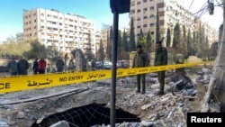 Police officers stand on the rubble of a damaged building at the site of a rocket attack, in central Damascus' Kafr Sousa neighborhood, Syria, Feb. 19, 2023. 