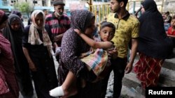 6일 팔레스타인 난민들이 머물고 있는 유엔 팔레스타인난민구호기구(UNRWA) 학교 시설에 이스라엘의 공습으로 다친 아이를 한 여성이 안고 이동하고 있다.