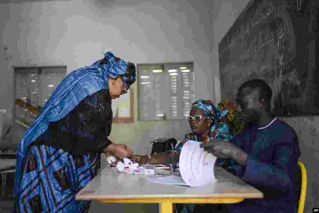 A woman dips his finger in ink after casting her vote inside a polling station during the presidential elections in Dakar, Senegal, March 24, 2024.