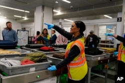 A worker points as people wait for the belongings at the Transportation Security Administration security area at the Hartsfield-Jackson Atlanta International Airport, Jan. 25, 2023, in Atlanta, Ga.