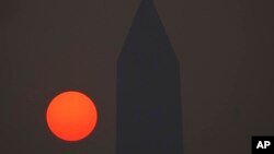 The sun rises behind the Washington Monument and a thick layer of smoke, June 8, 2023, in Washington.