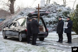 FILE - Pallbearers stand by the vehicle carrying the coffin of Boguslaw Wos, one of two Polish men killed in a missile explosion ahead of his funeral, in Przewodow, Poland, Nov. 19, 2022.