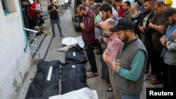 Mourners pray next to the bodies of Palestinians killed in Israeli strikes, amid the ongoing conflict between Israel and Hamas, during their funeral in Rafah, in the southern Gaza Strip, May 9, 2024.