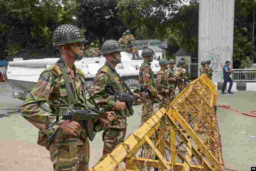 Army personnel stand guard behind a barrier during a curfew imposed following violence during protests against Prime Minister Sheikh Hasina and her government, in Dhaka, Aug. 5, 2024.
