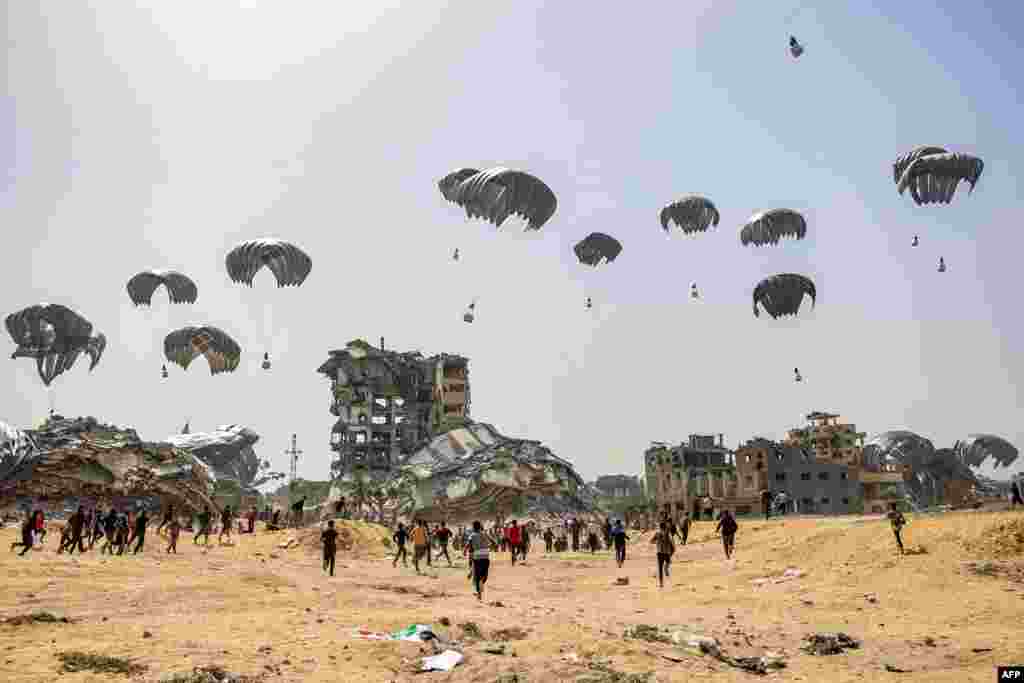 People rush to humanitarian aid packages dropped near destroyed buildings in the northern Gaza Strip, April 23, 2024, amid the ongoing conflict in the Palestinian territory between Israel and the militant group Hamas.