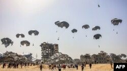 Луѓе трчаат кон пакетите со хуманитарна помош фрлени во близина на уништените згради во северниот дел на Појасот Газа, поради тековниот конфликт меѓу Израел и милитантната група Хамас.