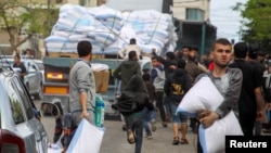 People grab flour bags from a truck after the Israeli military began evacuating Palestinian civilians ahead of a threatened assault on Rafah, amid the ongoing conflict between Israel and Hamas, in Rafah, in the southern Gaza Strip, May 6, 2024.