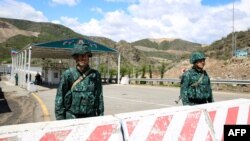 FILE - Men guard an Azerbaijani checkpoint set up at the entry of the Lachin Corridor, the Armenian-populated breakaway Nagorno-Karabakh region's only land link with Armenia, by a bridge across the Hakari river, on May 2, 2023. 