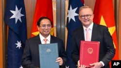 นายกรัฐมนตรีออสเตรเลีย แอนโทนี อัลบาเนซี และนายกรัฐมนตรีเวียดนาม ฝ่าม มิงห์ จิ๋งห์ แลกเปลี่ยนเอกสารระหว่างกัน หลังร่วมพิธีลงนามที่อาคารรัฐสภาออสเตรเลียน ที่กรุงแคนเบอร์รา เมื่อ 7 มี.ค. 2567