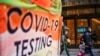 People wearing masks walk next to a COVID-19 testing site in New York City, December 12, 2022.