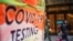 People wearing masks walk next to a COVID-19 testing site in New York City, December 12, 2022.