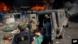 Paramedics carry an injured man into an ambulance after a Russian rocket attack on a food market in the city center of Kostiantynivka, Ukraine, Sept. 6, 2023. 