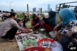 FILE - A woman buys fish from vendors next to the Mekong River in Phnom Penh, Jan. 4, 2023.