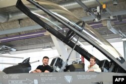 FILE - Ukrainian President Volodymyr Zelenskyy, left, and Danish Prime Minister Mette Frederiksen sit in a F-16 fighter jet in the hangar of the Skrydstrup Airbase in Vojens, northern Denmark, on Aug. 20, 2023.