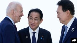 U.S. President Joe Biden, left, talks with Japan's Prime Minister Fumio Kishida and South Korean President Yoon Suk Yeol, right, ahead of a trilateral meeting on the sidelines of the G7 Summit in Hiroshima, Japan, May 21, 2023.